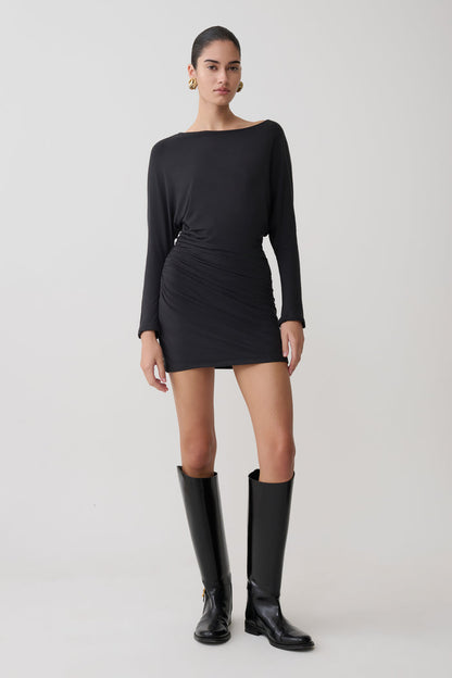 Woman wearing a black dress and knee-high boots on a white background.
